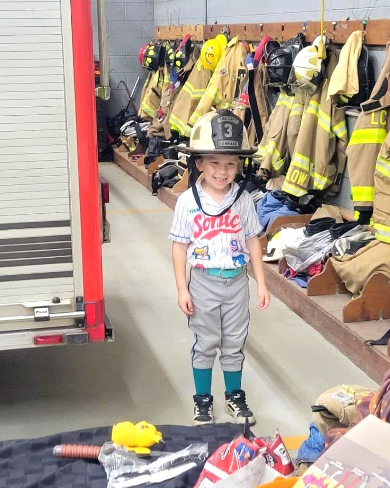 A young visitor tries on a firefighter helmet at Station 3